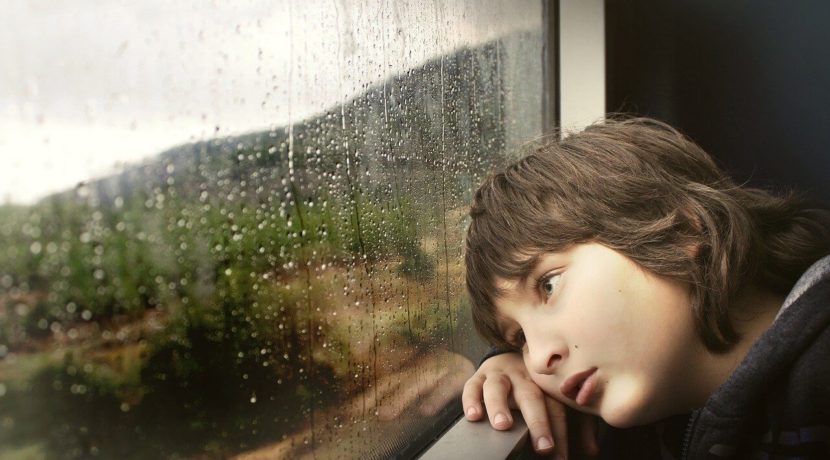 雨の日に窓の外を見つめる子供